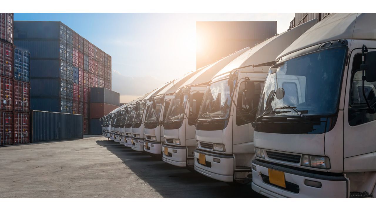 Trucks lined up next to shipping containers