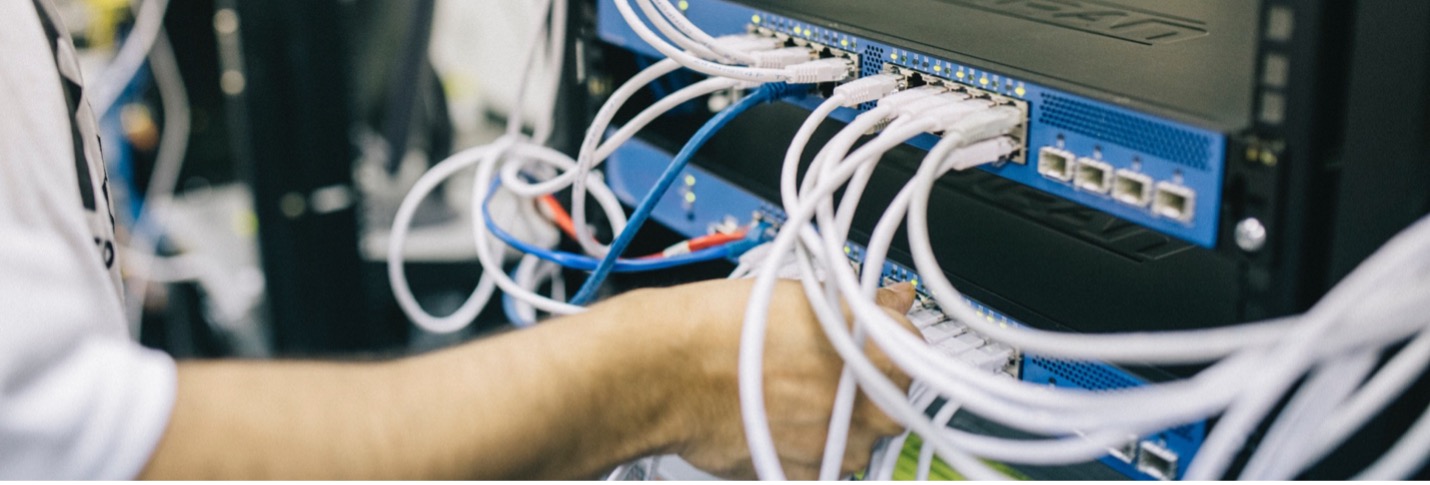 Man in server room connecting cables to ports